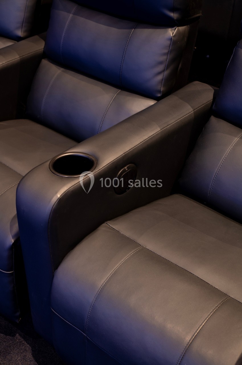 Fauteuils de cinéma en cuir noir avec accoudoirs équipés de porte-gobelets intégrés.