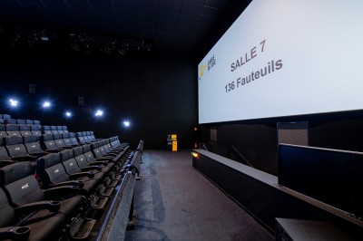Vue intérieure d'un espace moderne avec escalier, escalator rouge et murs sombres décorés de motifs colorés.