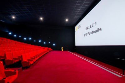Vue intérieure d'un espace moderne avec escalier, escalator rouge et murs sombres décorés de motifs colorés.