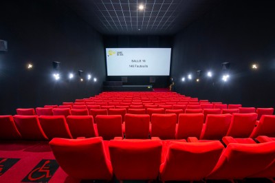Vue intérieure d'un espace moderne avec escalier, escalator rouge et murs sombres décorés de motifs colorés.