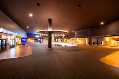 Vue intérieure d'un espace moderne avec escalier, escalator rouge et murs sombres décorés de motifs colorés.