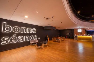 Vue intérieure d'un espace moderne avec escalier, escalator rouge et murs sombres décorés de motifs colorés.