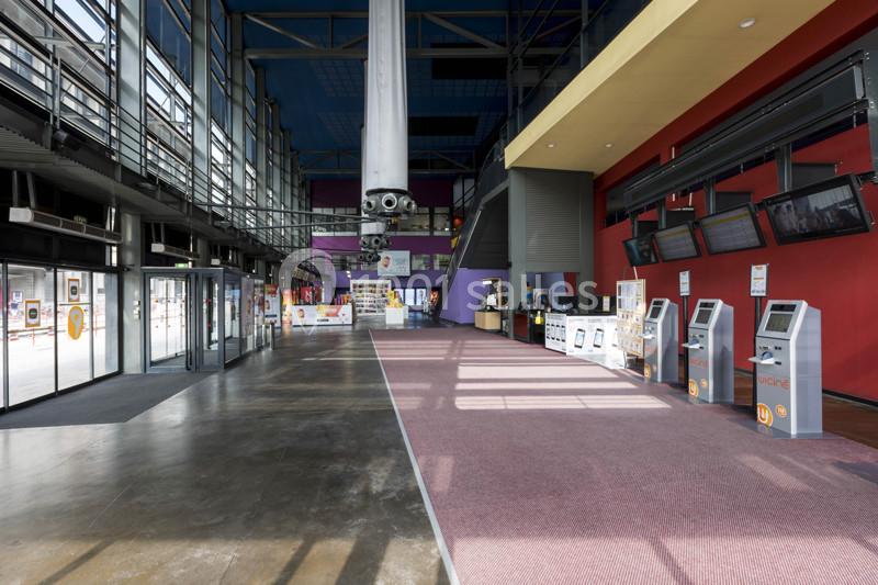 Hall spacieux avec guichets automatiques, comptoir d'accueil, murs colorés et grandes baies vitrées laissant entrer la…