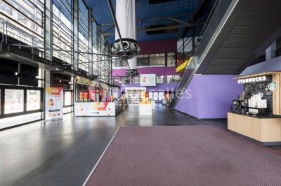 Salle de cinéma vide avec des rangées de sièges rouges et un éclairage tamisé.