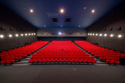 Vue intérieure d'un hall lumineux avec des stands colorés, des escaliers roulants et de grandes baies vitrées.