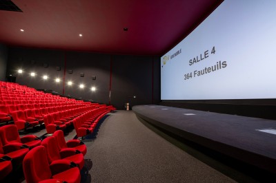 Vue intérieure d'un hall lumineux avec des stands colorés, des escaliers roulants et de grandes baies vitrées.