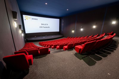 Vue intérieure d'un hall lumineux avec des stands colorés, des escaliers roulants et de grandes baies vitrées.
