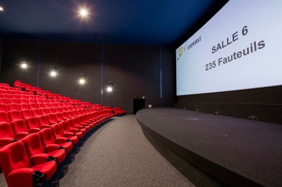 Vue intérieure d'un hall lumineux avec des stands colorés, des escaliers roulants et de grandes baies vitrées.