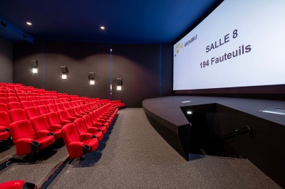 Vue intérieure d'un hall lumineux avec des stands colorés, des escaliers roulants et de grandes baies vitrées.