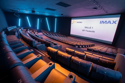 Vue intérieure d'un hall lumineux avec des stands colorés, des escaliers roulants et de grandes baies vitrées.
