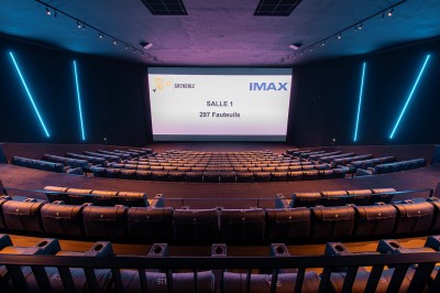 Vue intérieure d'un hall lumineux avec des stands colorés, des escaliers roulants et de grandes baies vitrées.