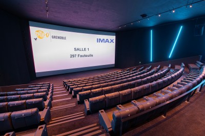 Vue intérieure d'un hall lumineux avec des stands colorés, des escaliers roulants et de grandes baies vitrées.