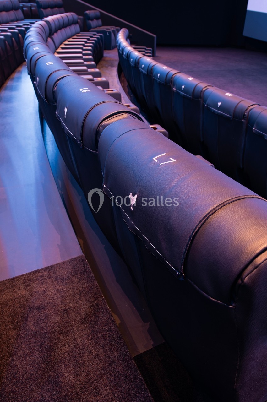Rangées de sièges en cuir noir alignés dans une salle de cinéma ou de conférence moderne.