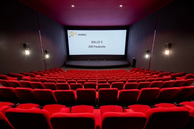 Vue intérieure d'un hall lumineux avec des stands colorés, des escaliers roulants et de grandes baies vitrées.