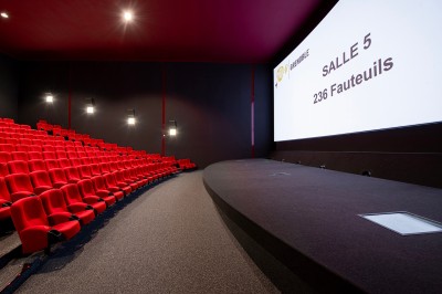 Vue intérieure d'un hall lumineux avec des stands colorés, des escaliers roulants et de grandes baies vitrées.