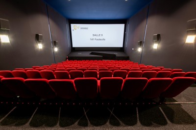Vue intérieure d'un hall lumineux avec des stands colorés, des escaliers roulants et de grandes baies vitrées.