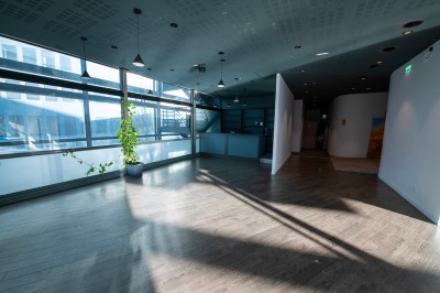 Vue intérieure d'un hall lumineux avec des stands colorés, des escaliers roulants et de grandes baies vitrées.