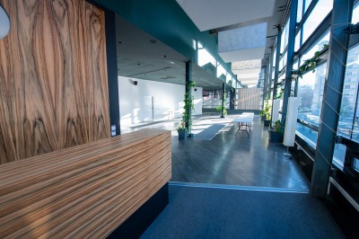 Vue intérieure d'un hall lumineux avec des stands colorés, des escaliers roulants et de grandes baies vitrées.