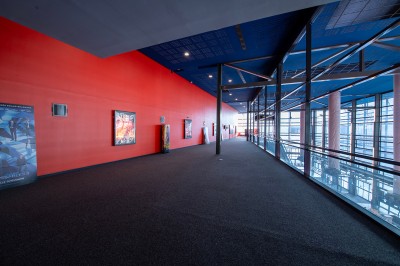 Vue intérieure d'un hall lumineux avec des stands colorés, des escaliers roulants et de grandes baies vitrées.