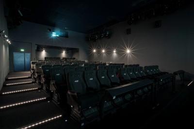 Salle de cinéma équipée de sièges 4DX avec écran lumineux affichant le logo 4DX, éclairage tamisé.