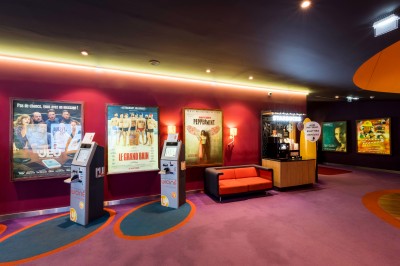 Salle de cinéma équipée de sièges 4DX avec écran lumineux affichant le logo 4DX, éclairage tamisé.