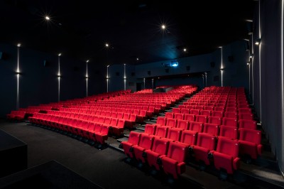 Salle de cinéma équipée de sièges 4DX avec écran lumineux affichant le logo 4DX, éclairage tamisé.