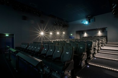 Salle de cinéma équipée de sièges 4DX avec écran lumineux affichant le logo 4DX, éclairage tamisé.