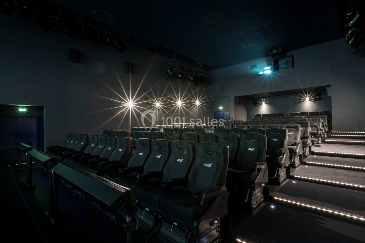 Salle de cinéma moderne avec sièges inclinables, éclairage tamisé et projecteurs au plafond.