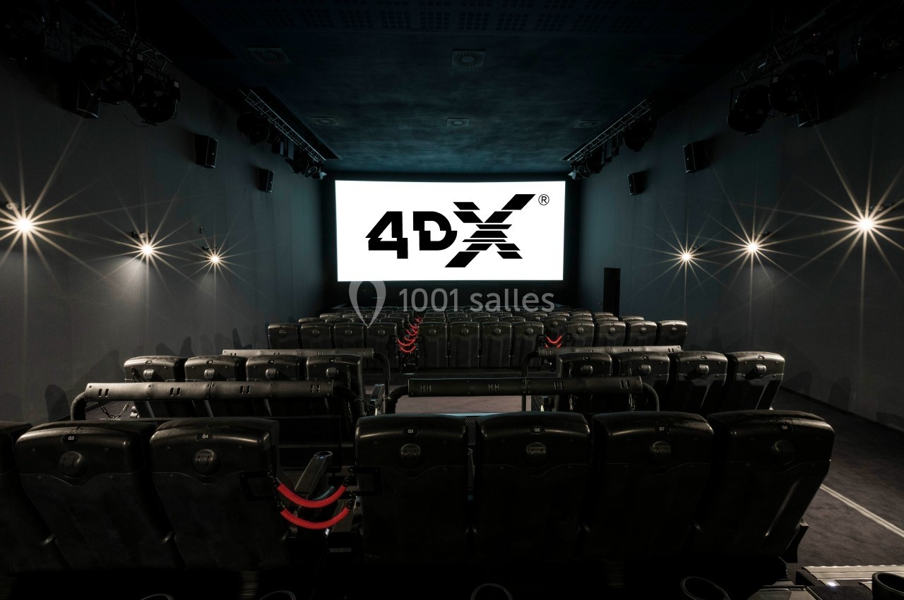 Salle de cinéma équipée de sièges 4DX avec écran allumé, éclairage tamisé et ambiance immersive.
