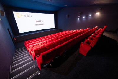 Salle de cinéma avec des rangées de fauteuils rouges et un écran affichant ’Salle 1, 318 fauteuils’.