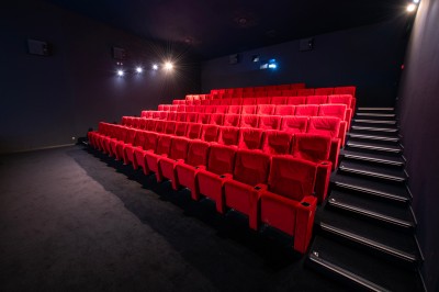 Salle de cinéma avec des rangées de fauteuils rouges et un écran affichant ’Salle 1, 318 fauteuils’.