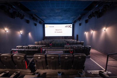 Salle de cinéma avec des rangées de fauteuils rouges et un écran affichant ’Salle 1, 318 fauteuils’.