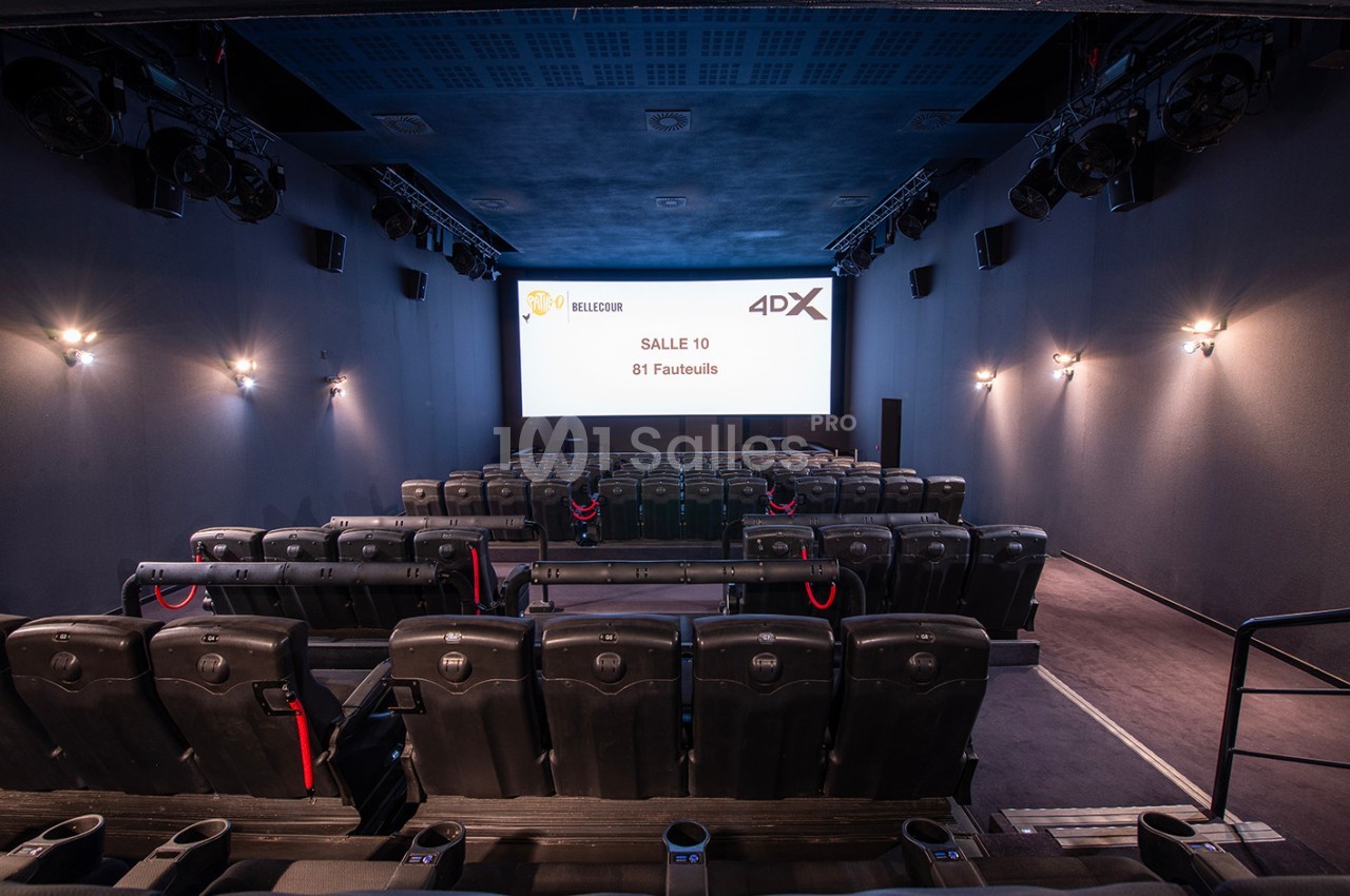Salle de cinéma vide avec sièges noirs, écran affichant ’Salle 10, 81 fauteuils’ et éclairage mural tamisé.