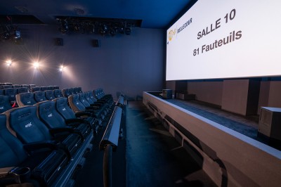 Salle de cinéma avec des rangées de fauteuils rouges et un écran affichant ’Salle 1, 318 fauteuils’.
