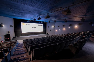Salle de cinéma avec des rangées de fauteuils rouges et un écran affichant ’Salle 1, 318 fauteuils’.