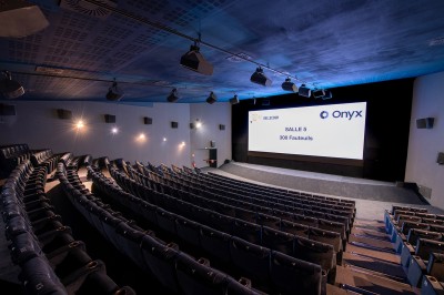 Salle de cinéma avec des rangées de fauteuils rouges et un écran affichant ’Salle 1, 318 fauteuils’.