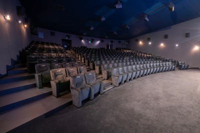 Salle de cinéma avec des rangées de fauteuils rouges et un écran affichant ’Salle 1, 318 fauteuils’.