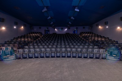 Salle de cinéma avec des rangées de fauteuils rouges et un écran affichant ’Salle 1, 318 fauteuils’.
