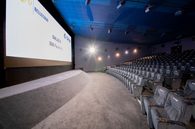 Salle de cinéma avec des rangées de fauteuils rouges et un écran affichant ’Salle 1, 318 fauteuils’.