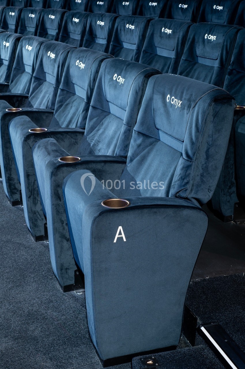Rangée de fauteuils de cinéma bleus avec porte-gobelets intégrés et marquage de siège ’A’.