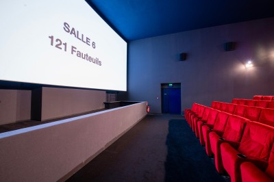 Salle de cinéma avec des rangées de fauteuils rouges et un écran affichant ’Salle 1, 318 fauteuils’.