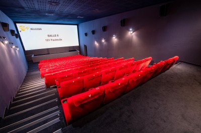 Salle de cinéma avec des rangées de fauteuils rouges et un écran affichant ’Salle 1, 318 fauteuils’.