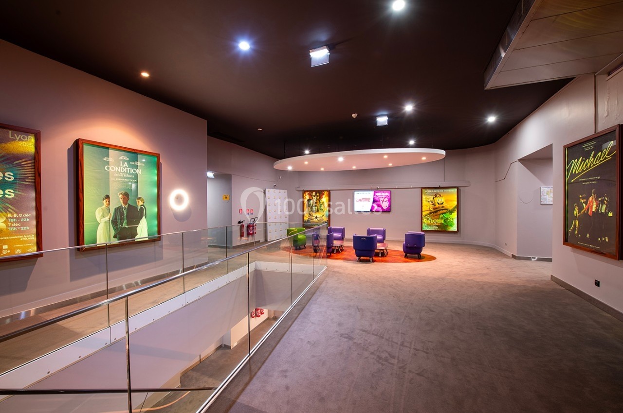 Espace intérieur d'un cinéma avec affiches de films sur les murs, fauteuils et éclairage moderne.