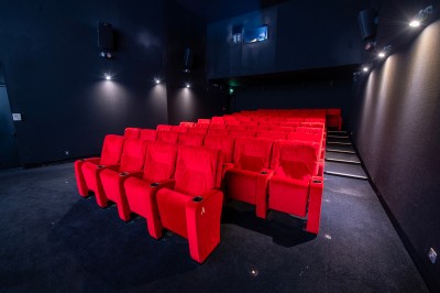 Salle de cinéma avec des rangées de fauteuils rouges et un écran affichant ’Salle 1, 318 fauteuils’.