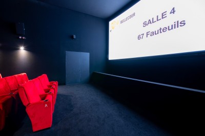 Salle de cinéma avec des rangées de fauteuils rouges et un écran affichant ’Salle 1, 318 fauteuils’.