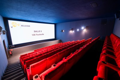 Salle de cinéma avec des rangées de fauteuils rouges et un écran affichant ’Salle 1, 318 fauteuils’.