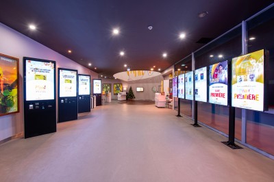 Salle de cinéma avec des rangées de fauteuils rouges et un écran affichant ’Salle 1, 318 fauteuils’.