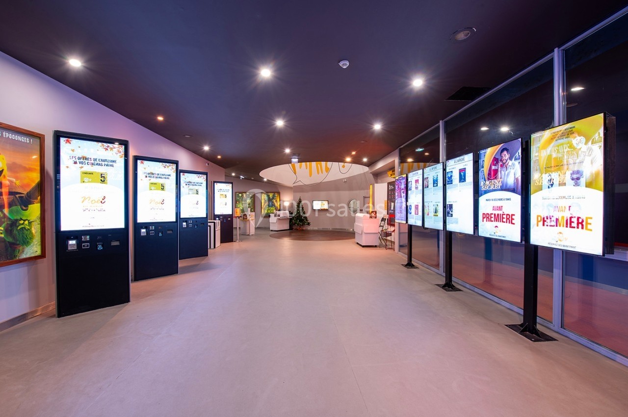 Vue d'un hall moderne avec des écrans numériques affichant des affiches et des informations, éclairage lumineux.