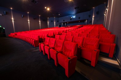 Salle de cinéma avec des rangées de fauteuils rouges et un écran affichant ’Salle 1, 318 fauteuils’.