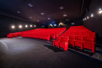 Salle de cinéma avec des rangées de fauteuils rouges et un écran affichant ’Salle 1, 318 fauteuils’.